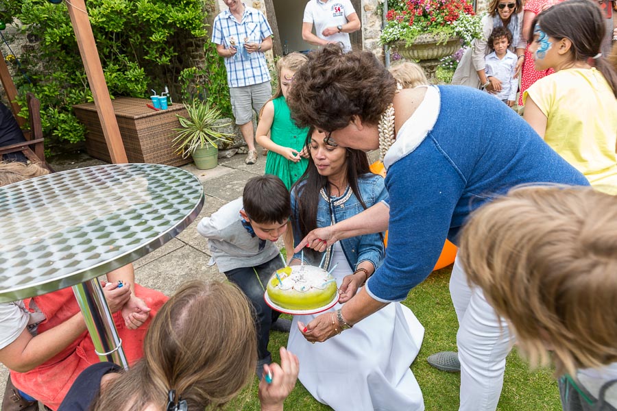 Eric is blowing out the candles while Genevieve and Mama are overseeing it all.