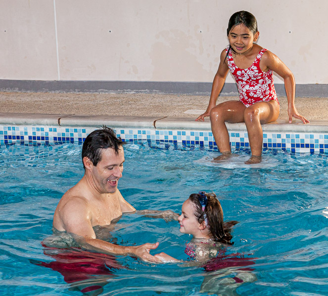 Mikee is looking at Tim Ford teaching Lara how to swim